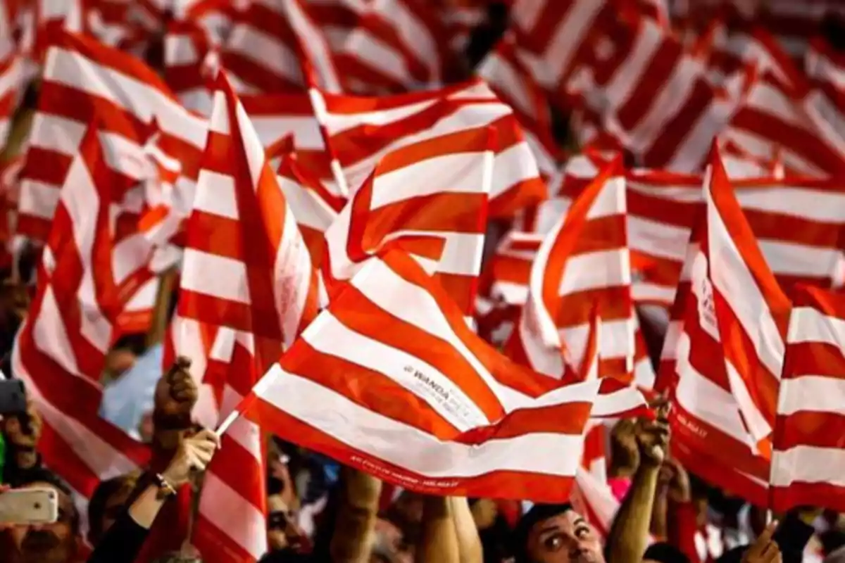 People waving red and white flags at a sporting event.