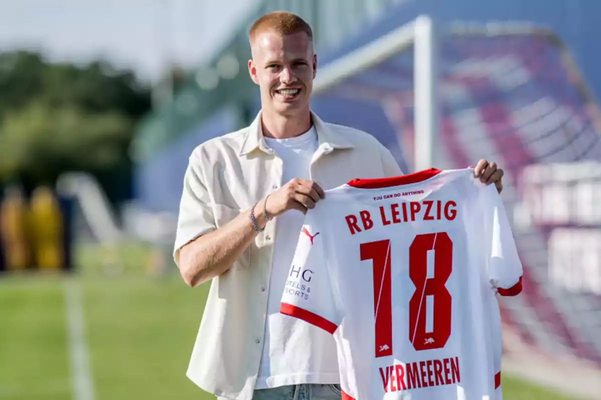 A man holding an RB Leipzig jersey with the number 18 and the name 