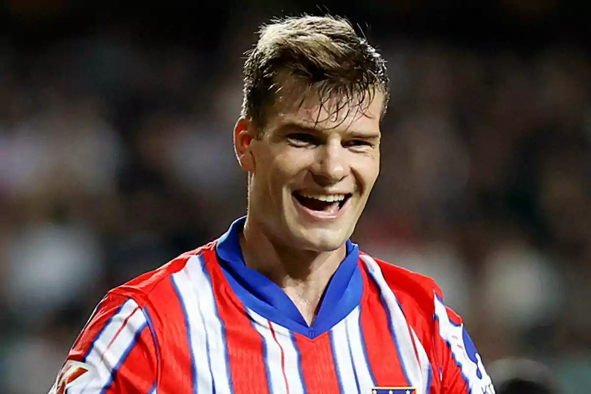 A soccer player smiles while wearing a red, white and blue striped jersey.