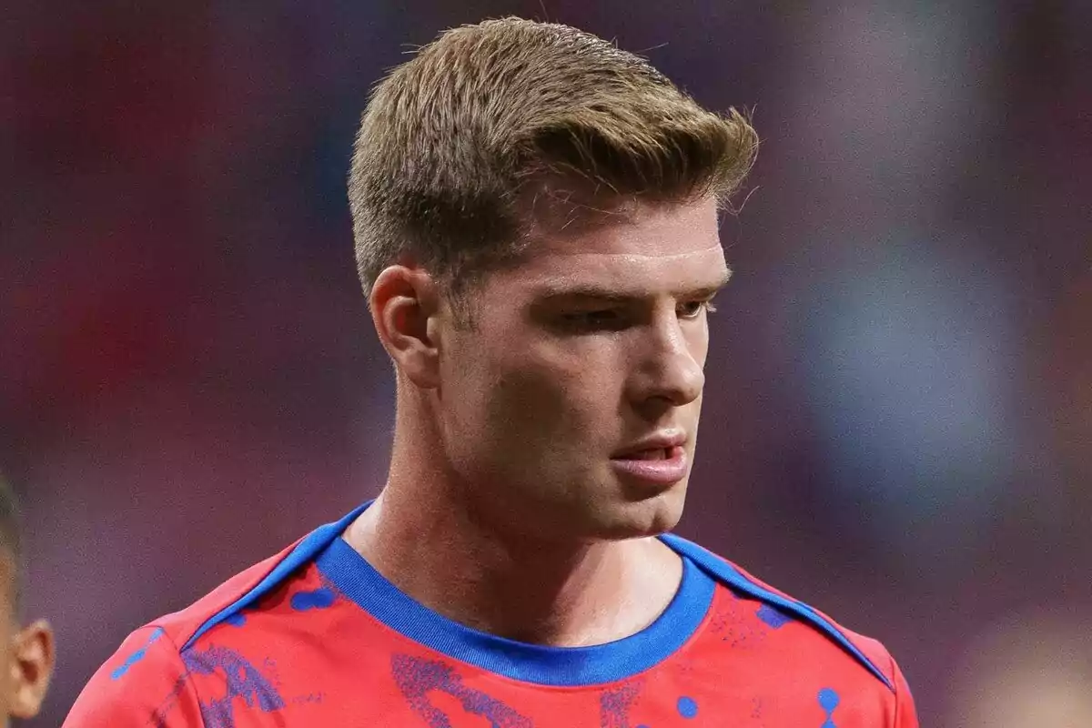 A man in a red and blue shirt on a football field.