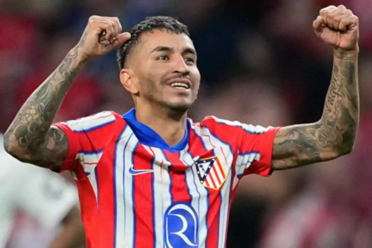 Football player celebrating with his arms raised while wearing the Atletico Madrid shirt.