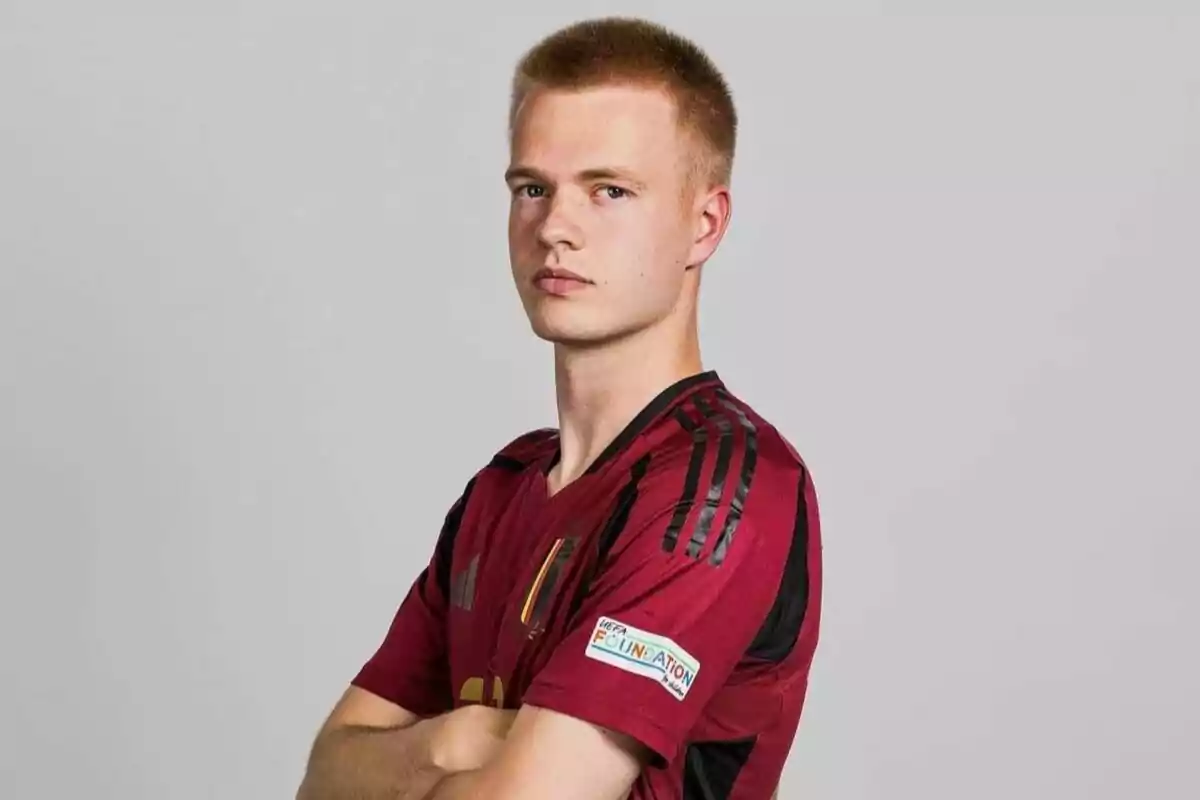 A man in a red and black soccer jersey posing with his arms crossed.