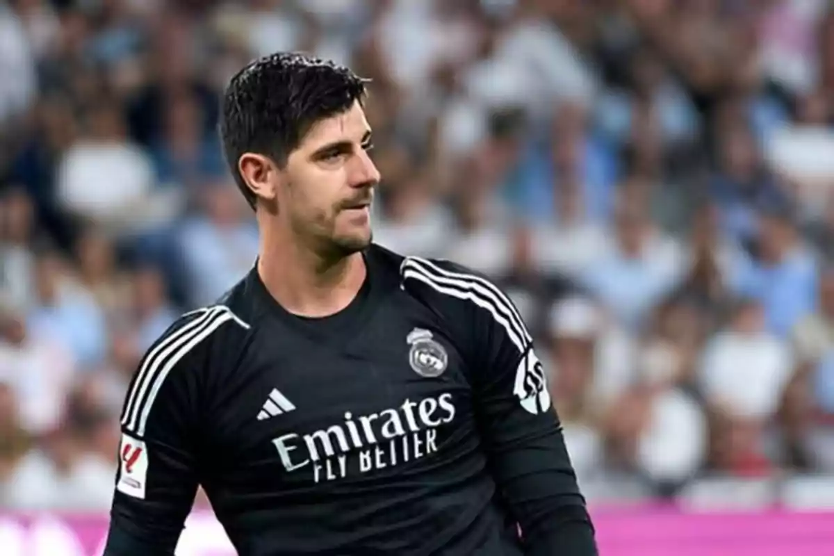 A football player in a black Real Madrid uniform on the playing field.