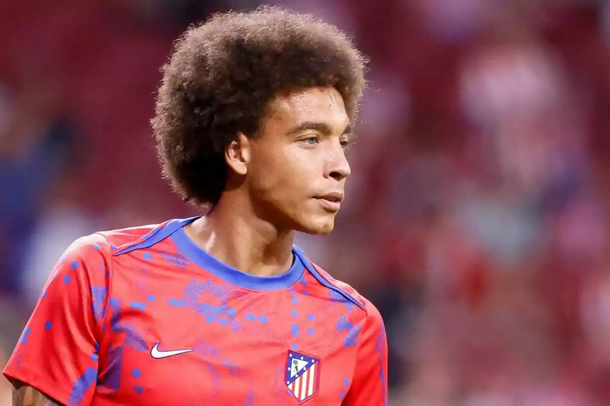 A football player wearing a red Atlético de Madrid training shirt.