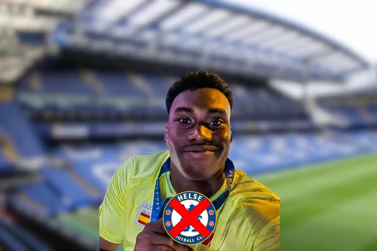 A smiling man with a medal and a crossed-out symbol of a football team in a stadium.