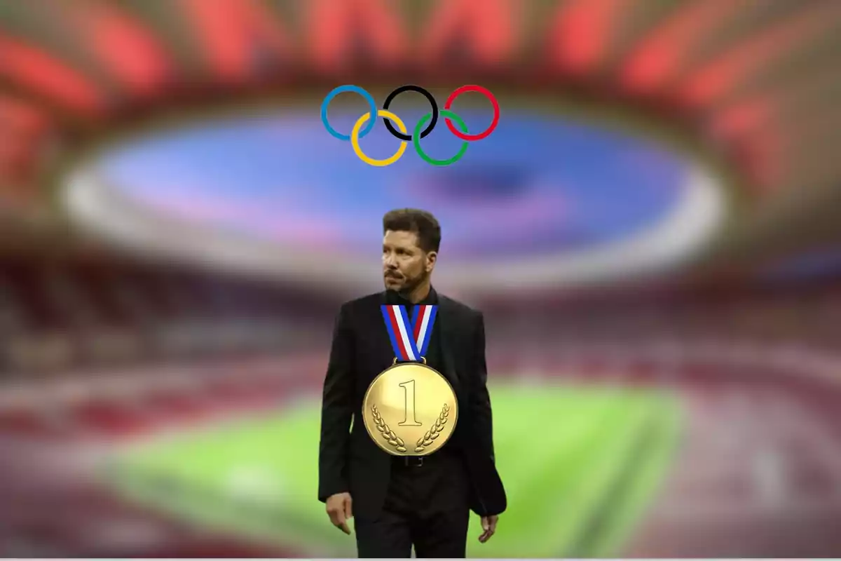 A man in a black suit and a gold medal with the number one, standing in a stadium with the Olympic rings in the background.