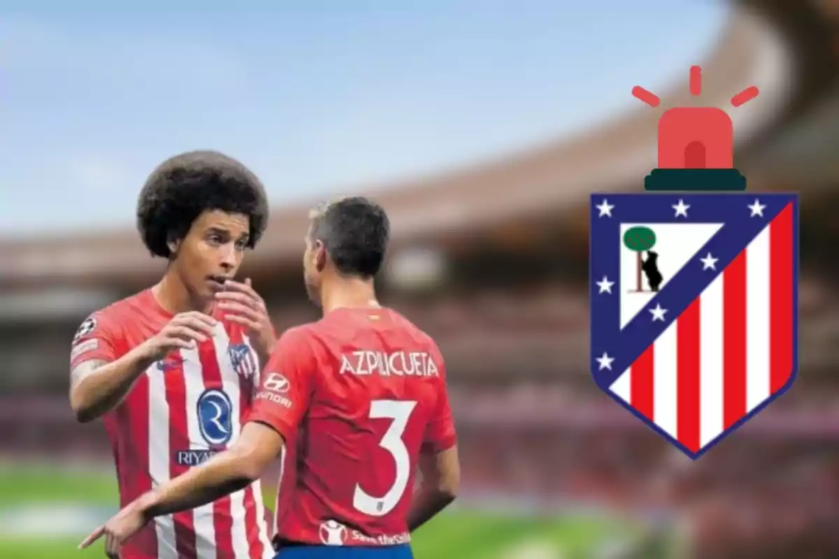 Two Atlético de Madrid players chatting on the pitch with the team's crest on the right.