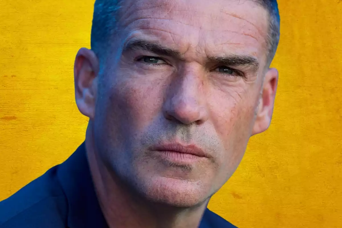 Portrait of a man with a serious expression on a yellow background.