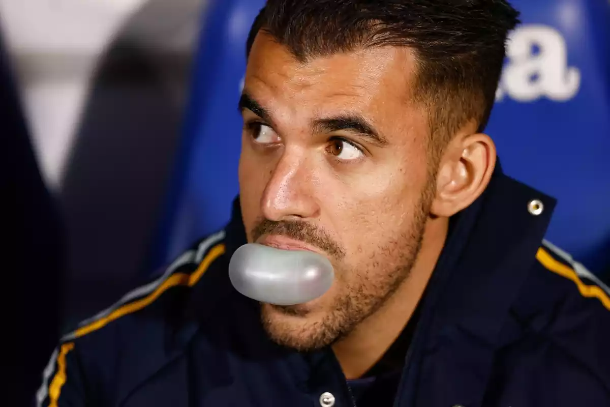 Dani Ceballos blowing a bubble with a piece of gum while sitting on the bench