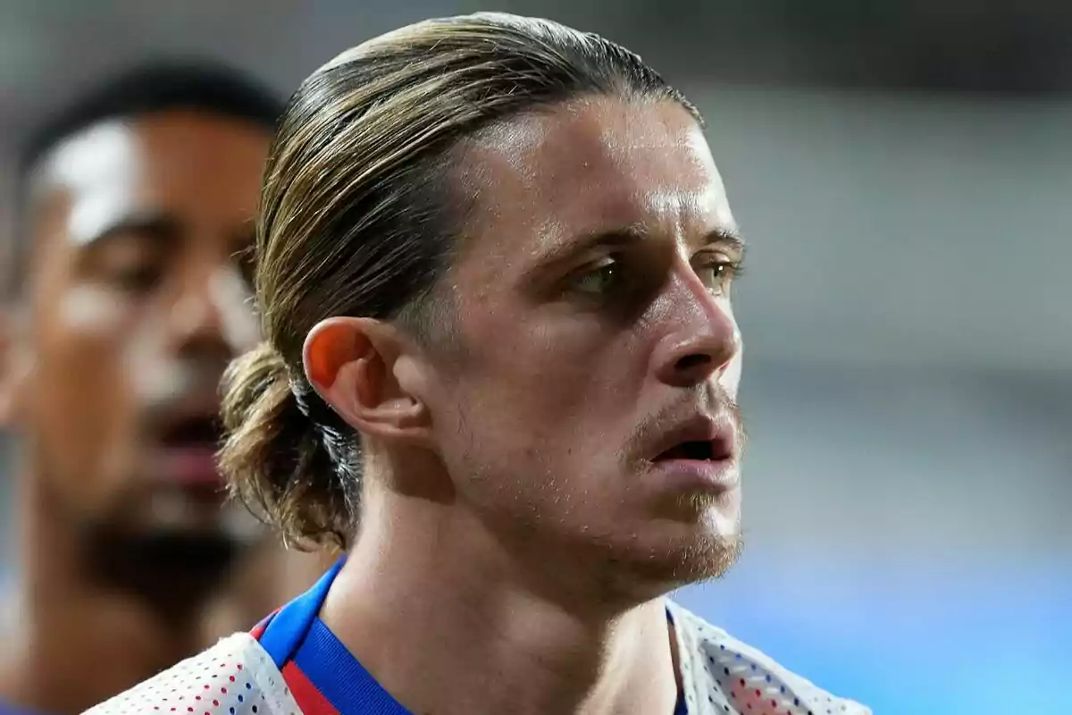 A soccer player with his hair tied back and a serious expression during a match.