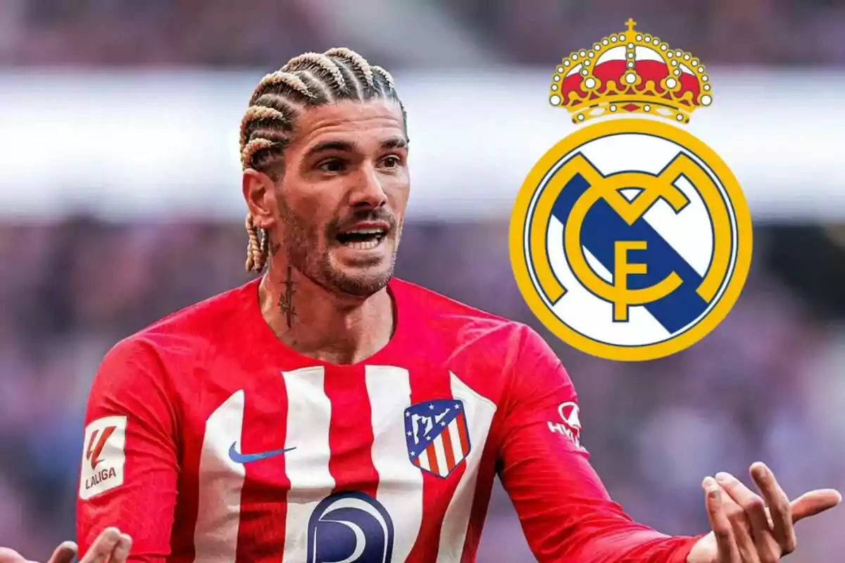 Football player in Atlético de Madrid uniform gesturing with his hands and the Real Madrid logo in the background.