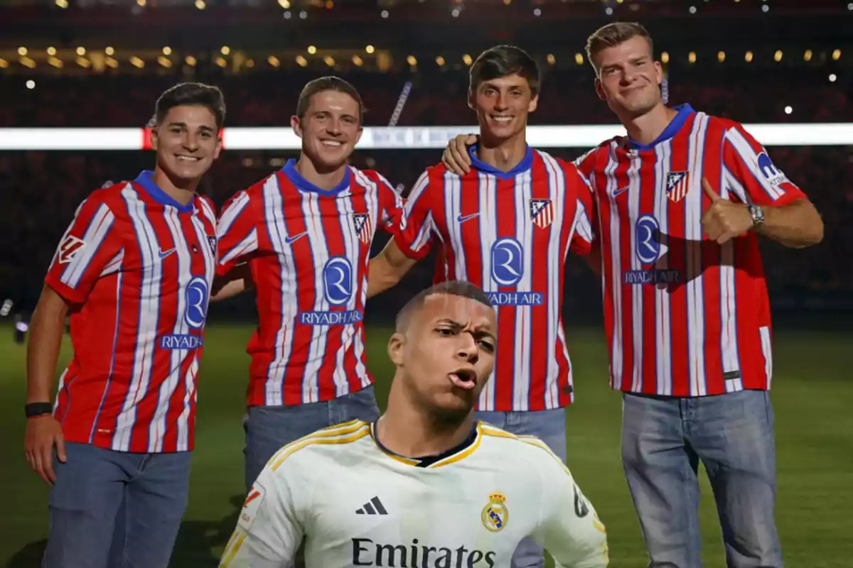 Five people pose for a photo in a stadium, four of them wearing Atlético de Madrid shirts and one wearing a Real Madrid shirt.