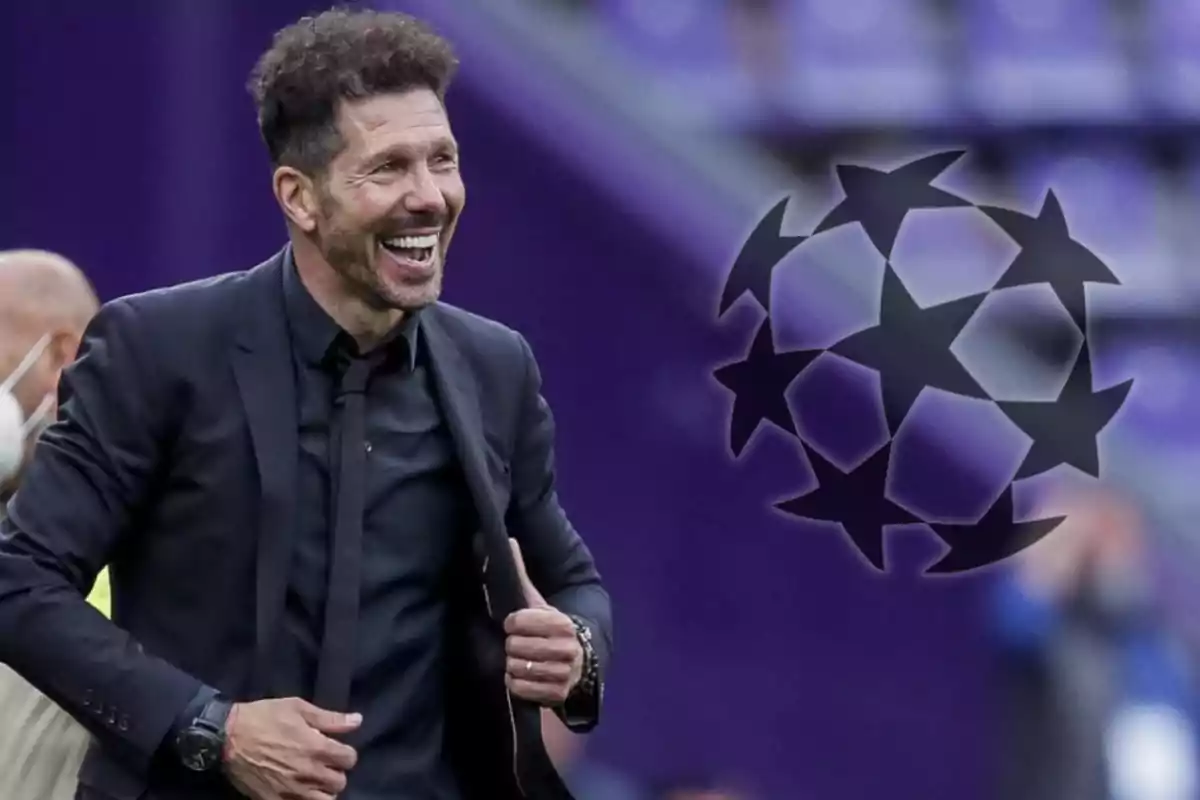 A smiling man in a black suit next to the UEFA Champions League logo.