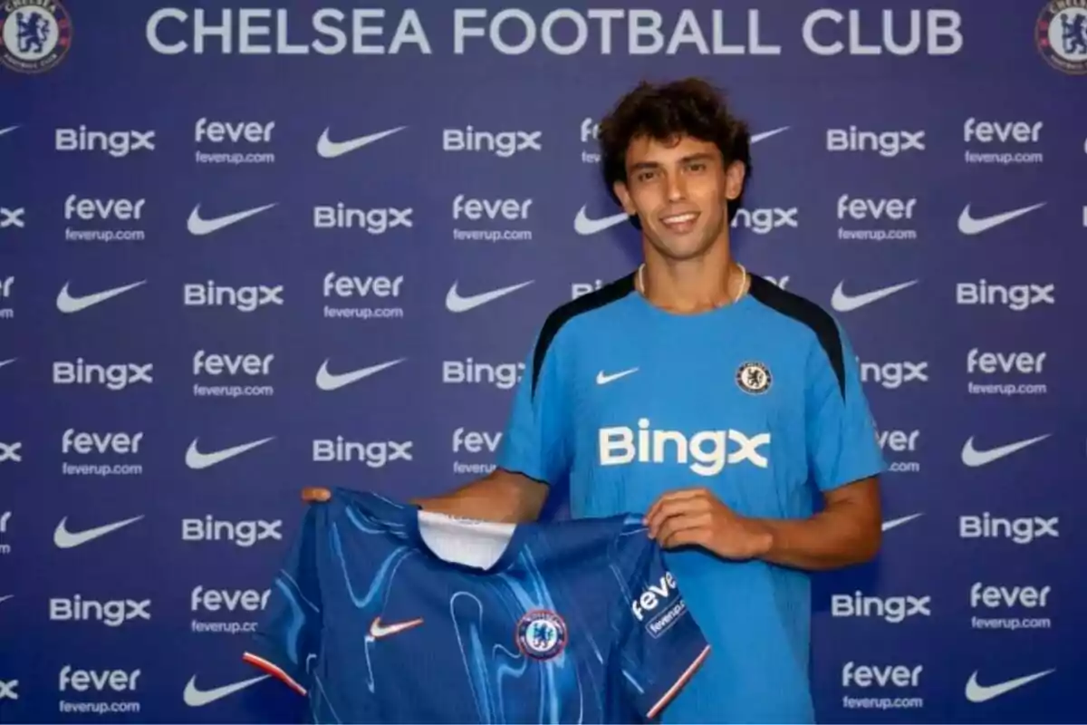 A football player wearing a Chelsea FC shirt at an official presentation.