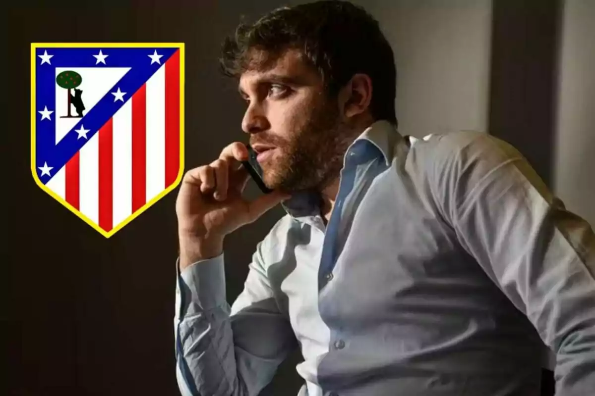 A man talking on the phone with the Atlético de Madrid crest next to him.