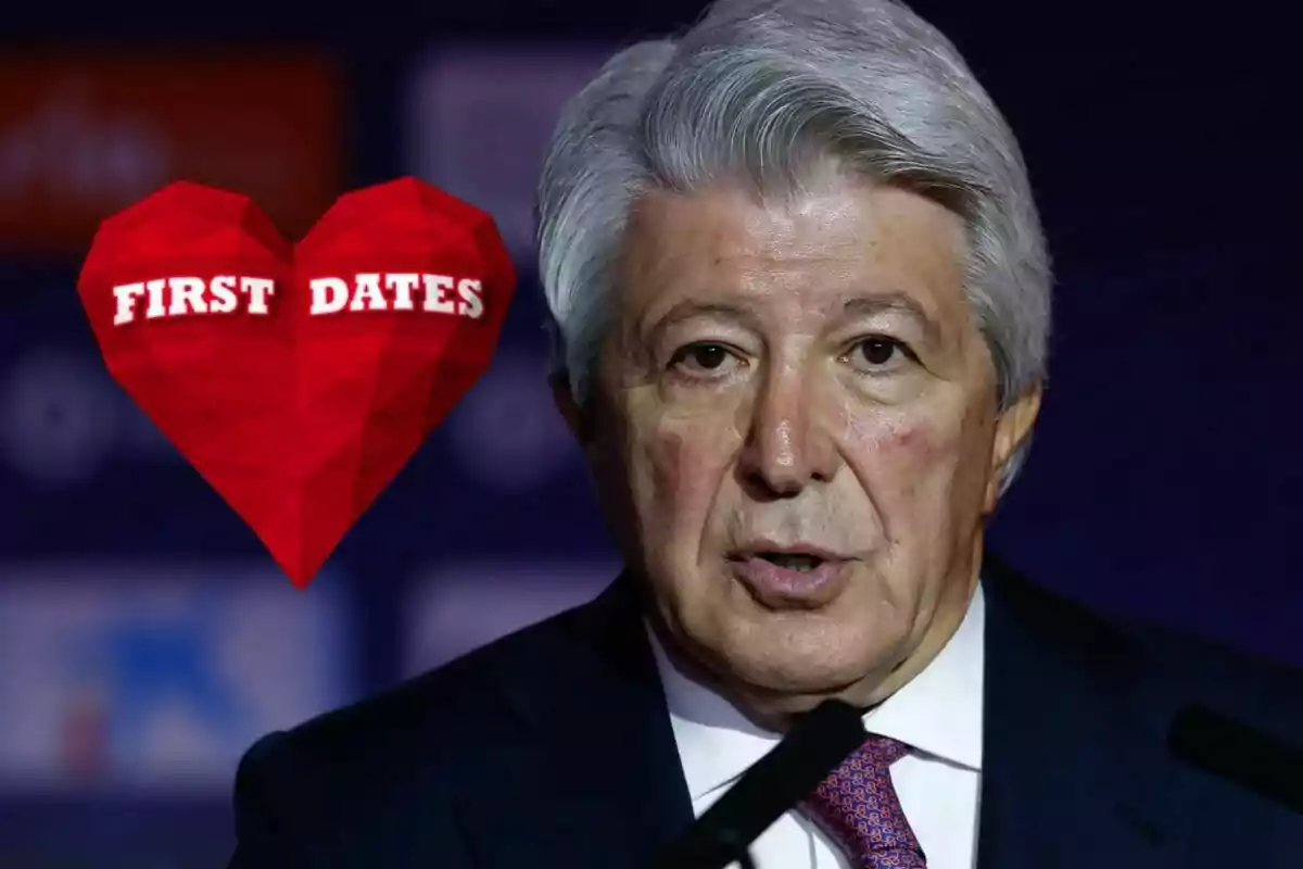 Gray-haired man in a dark suit speaking into a microphone with a red heart that says "First Dates" to his left.