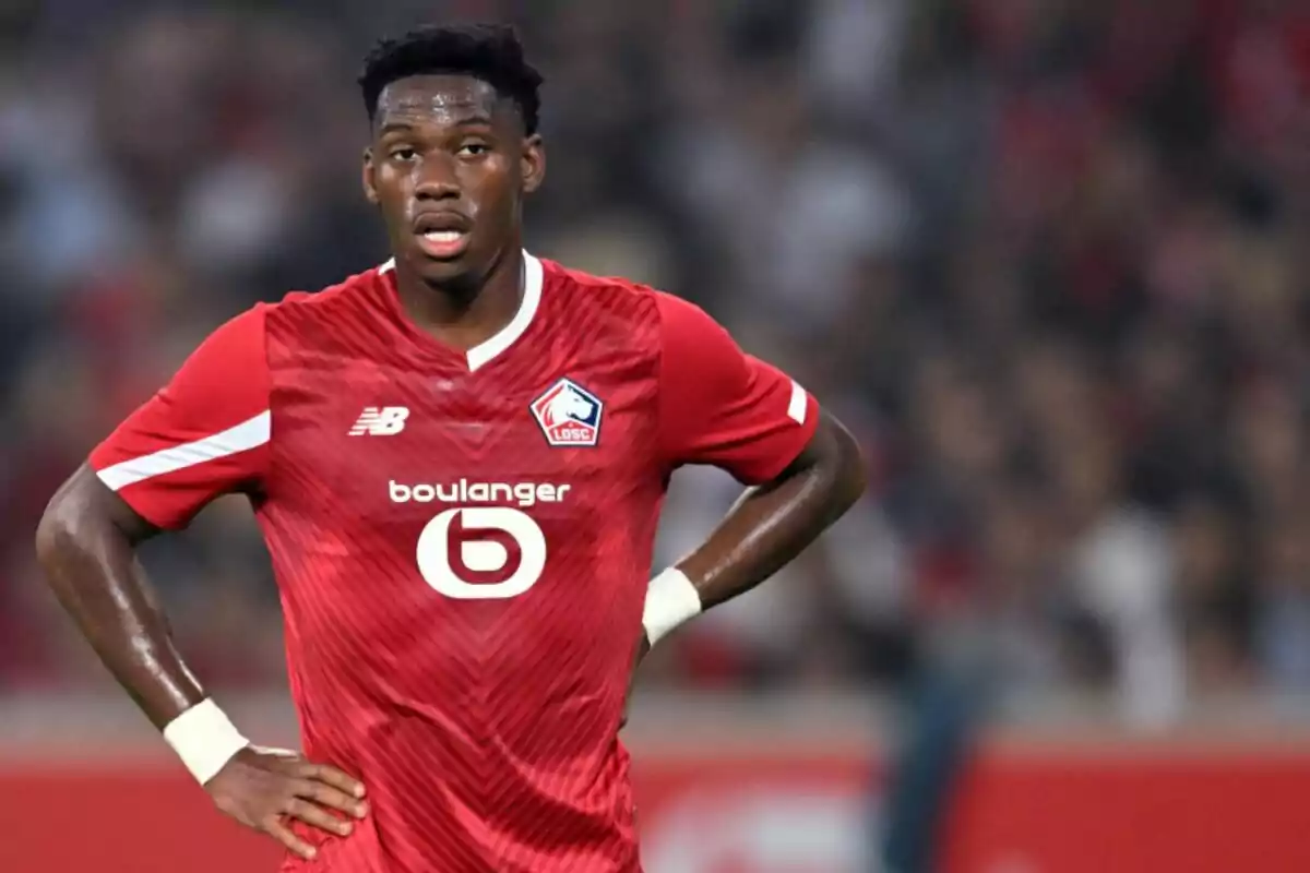 Football player in red uniform of LOSC Lille team on the playing field.