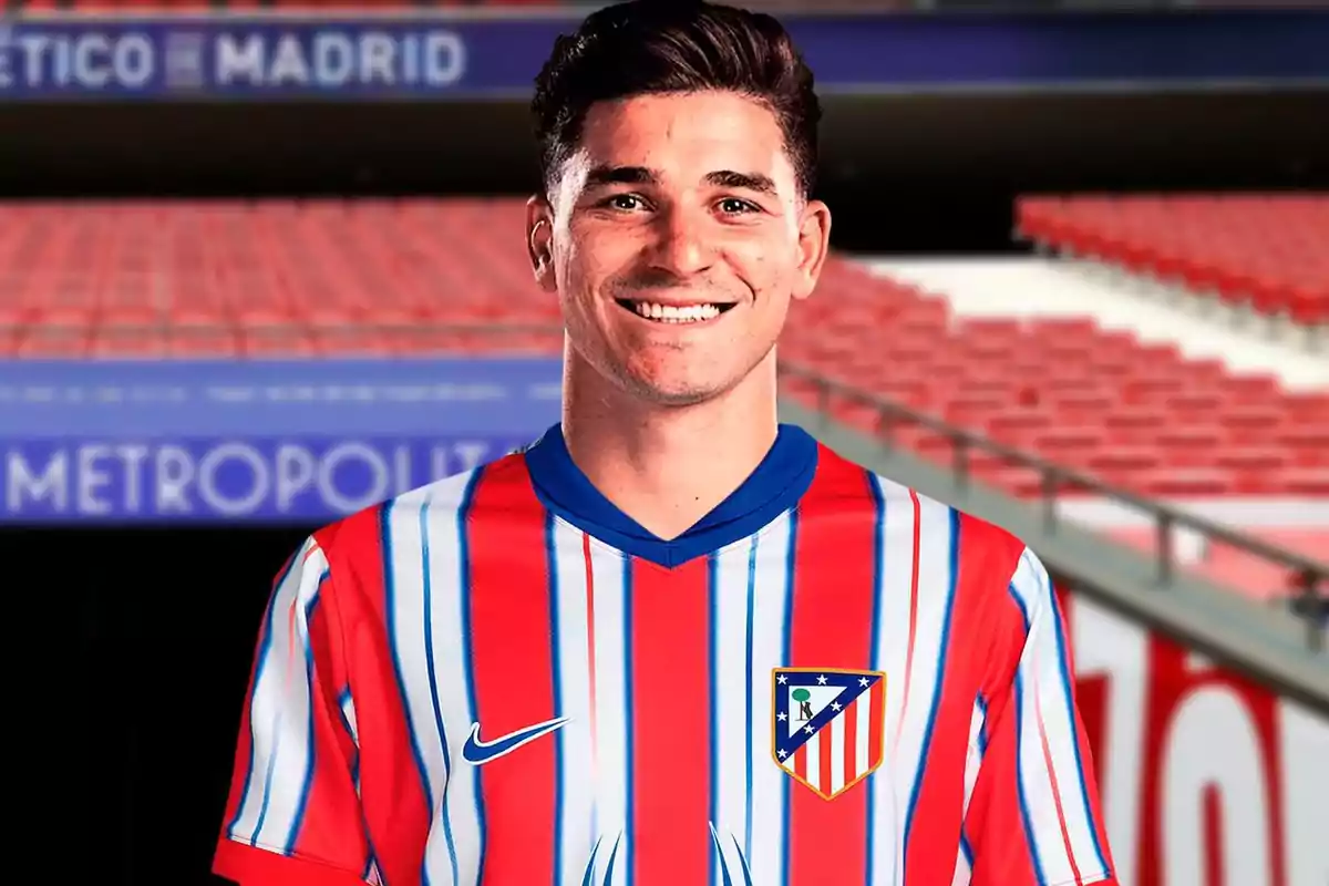 A soccer player wearing an Atlético de Madrid shirt smiles in a stadium.