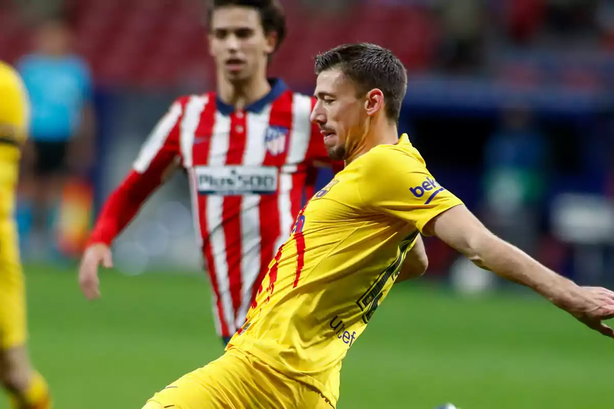 A Barcelona player in a yellow uniform fights for the ball with an Atlético de Madrid player in a red and white uniform during a football match.