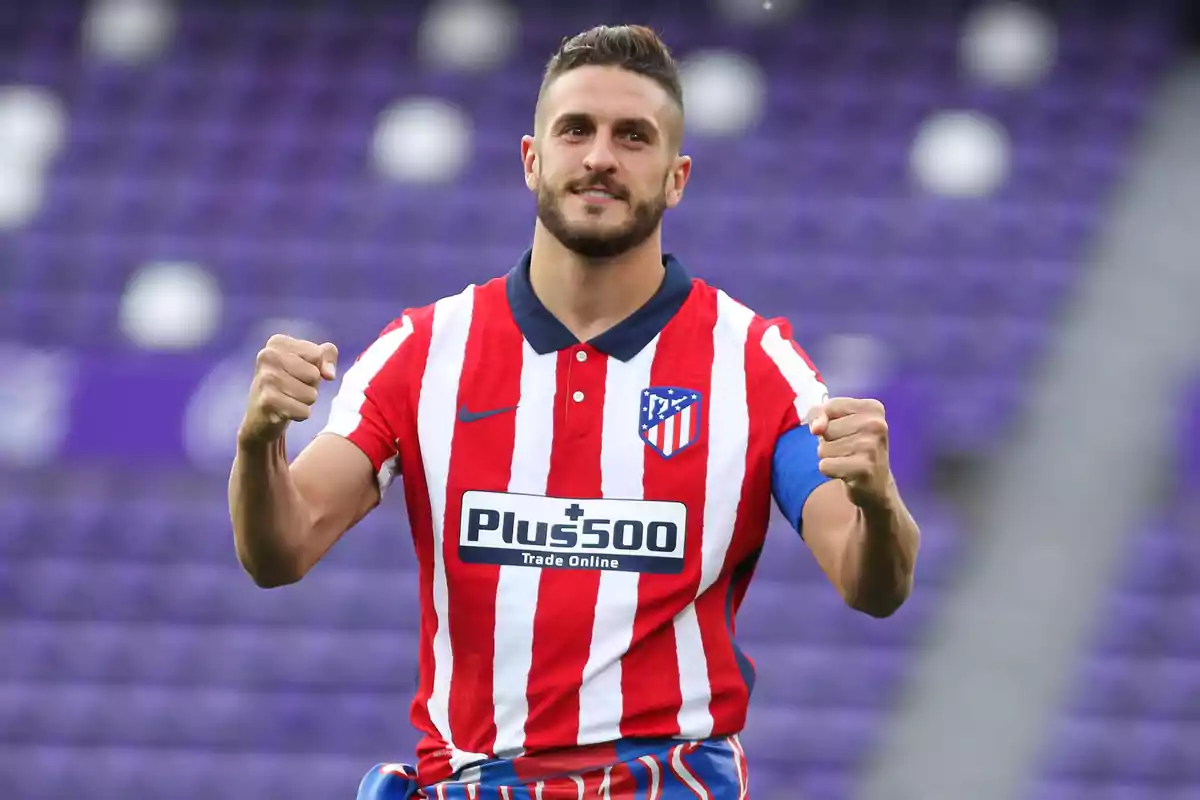 Football player in Atlético de Madrid uniform celebrating on the field.