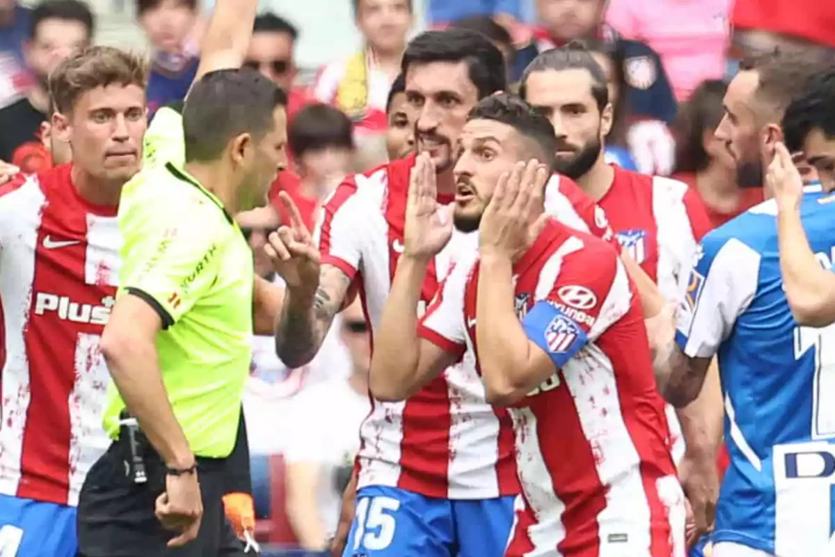 Atletico Madrid football players argue with the referee during a match.