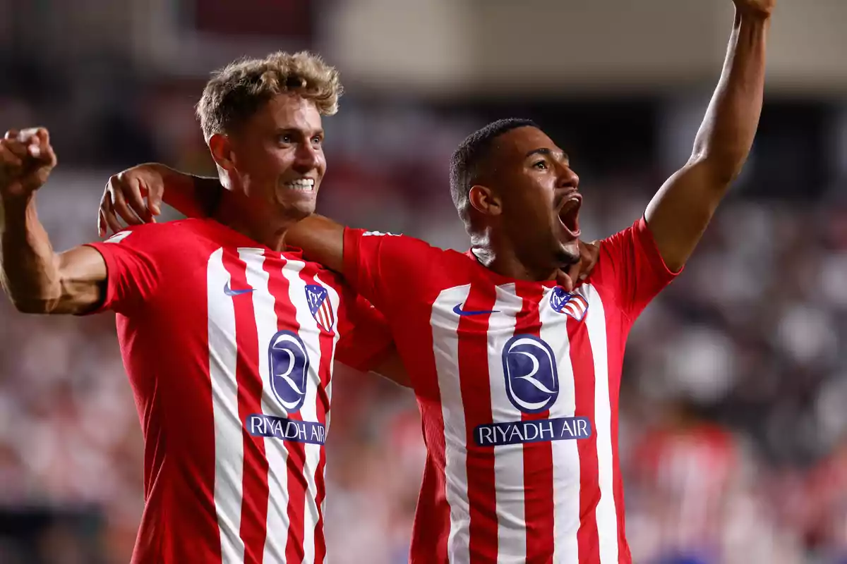 Two football players celebrating a goal wearing Atlético de Madrid shirts.