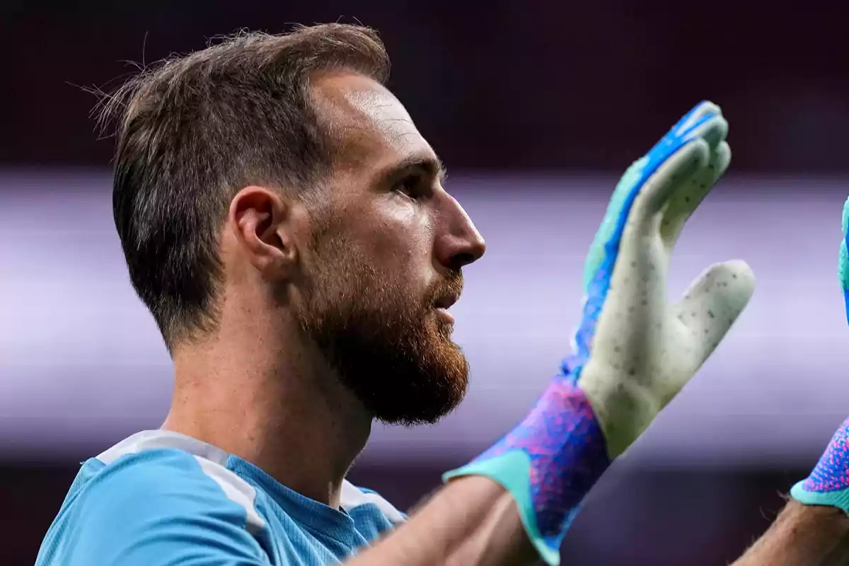 A soccer goalkeeper with gloves raising his hands.