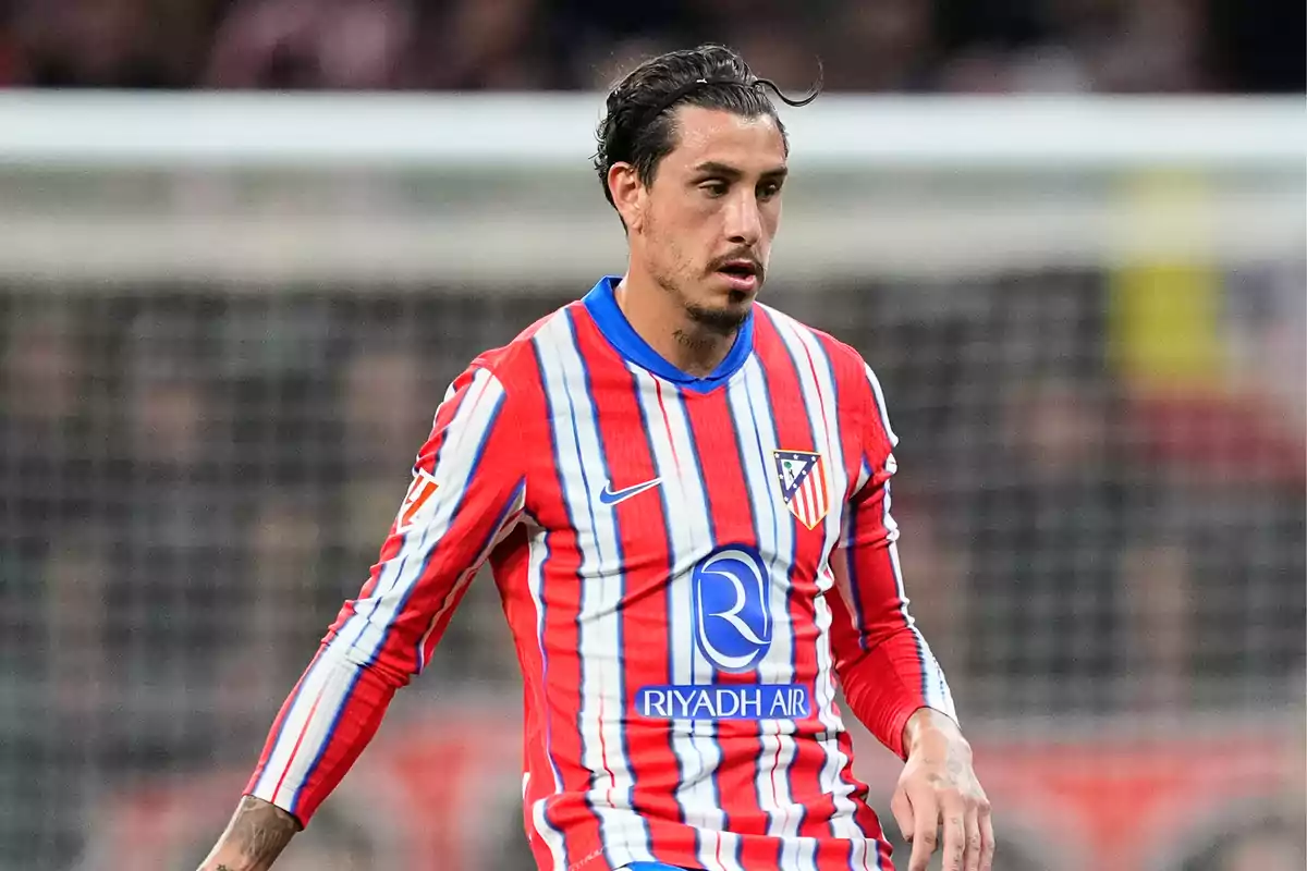 Football player in Atlético de Madrid uniform on the playing field.