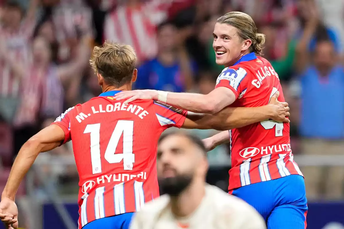 Two soccer players celebrating a goal in red and white jerseys.