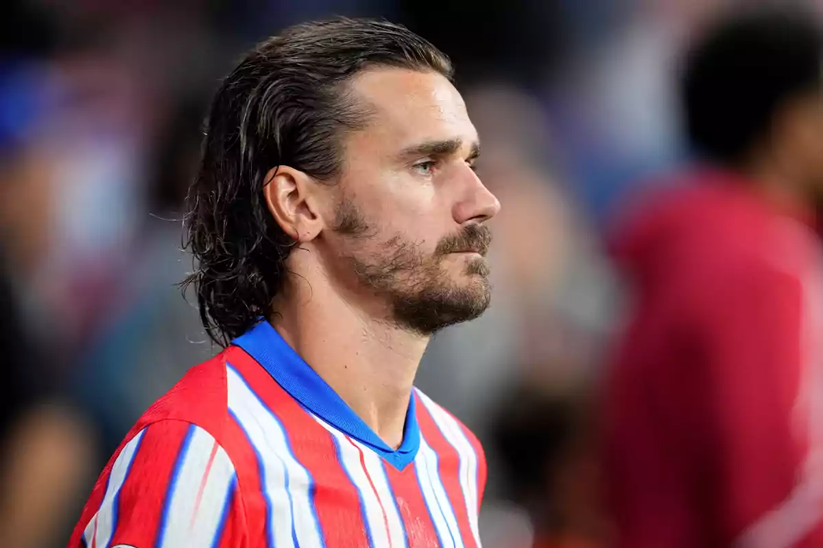 A soccer player wearing a red, white and blue striped jersey, looking to the right.