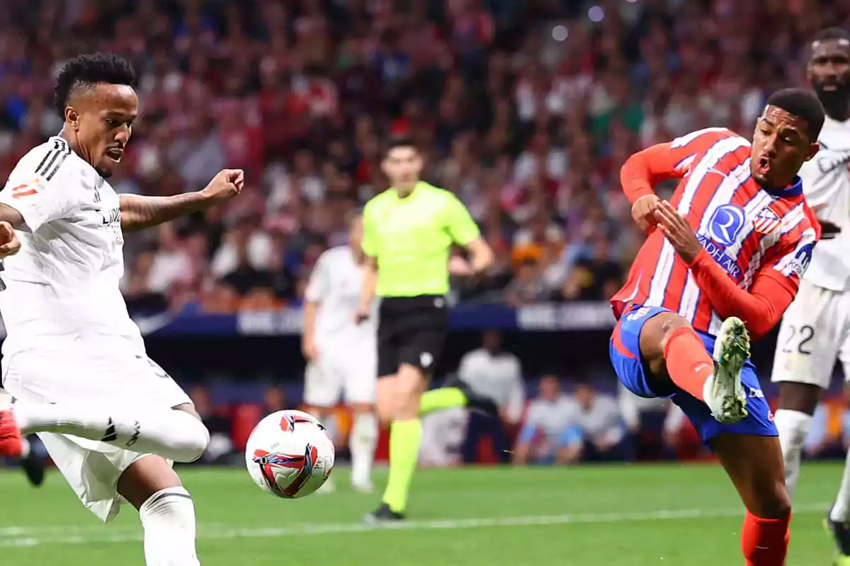 Two soccer players compete for the ball during a match, one in a white uniform and the other in a red and white uniform, while a referee watches in the background.