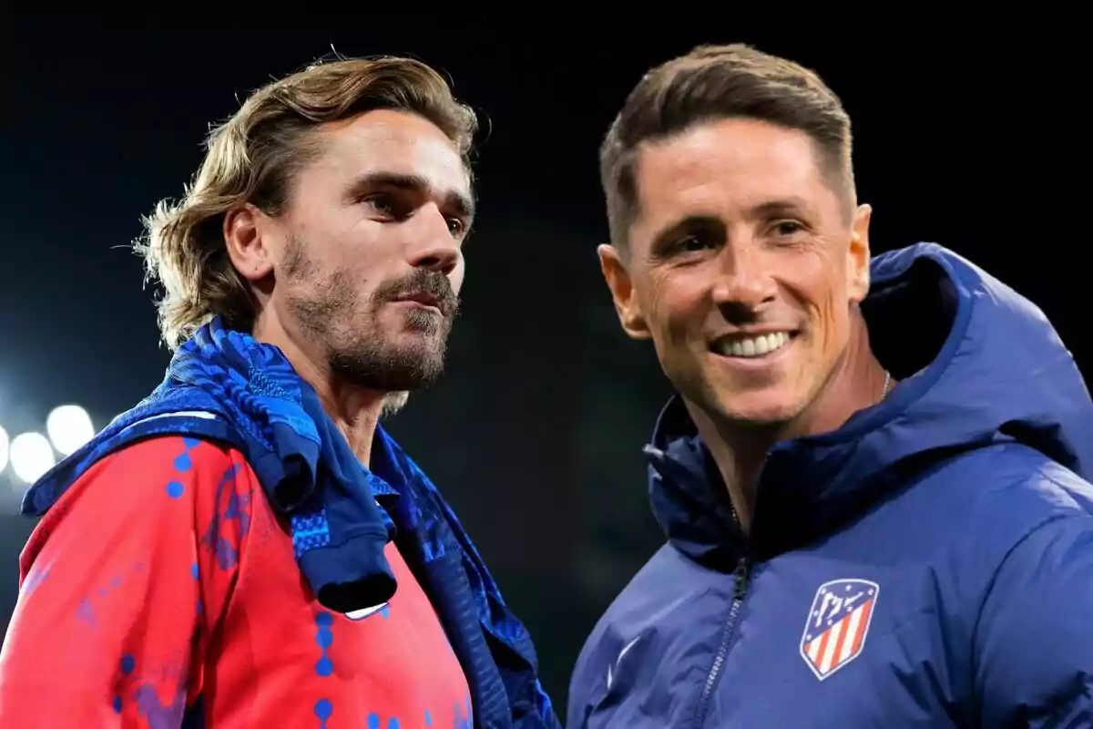 Two men in Atlético de Madrid sportswear, one in a red shirt and the other in a blue jacket, chat and smile in a night setting.