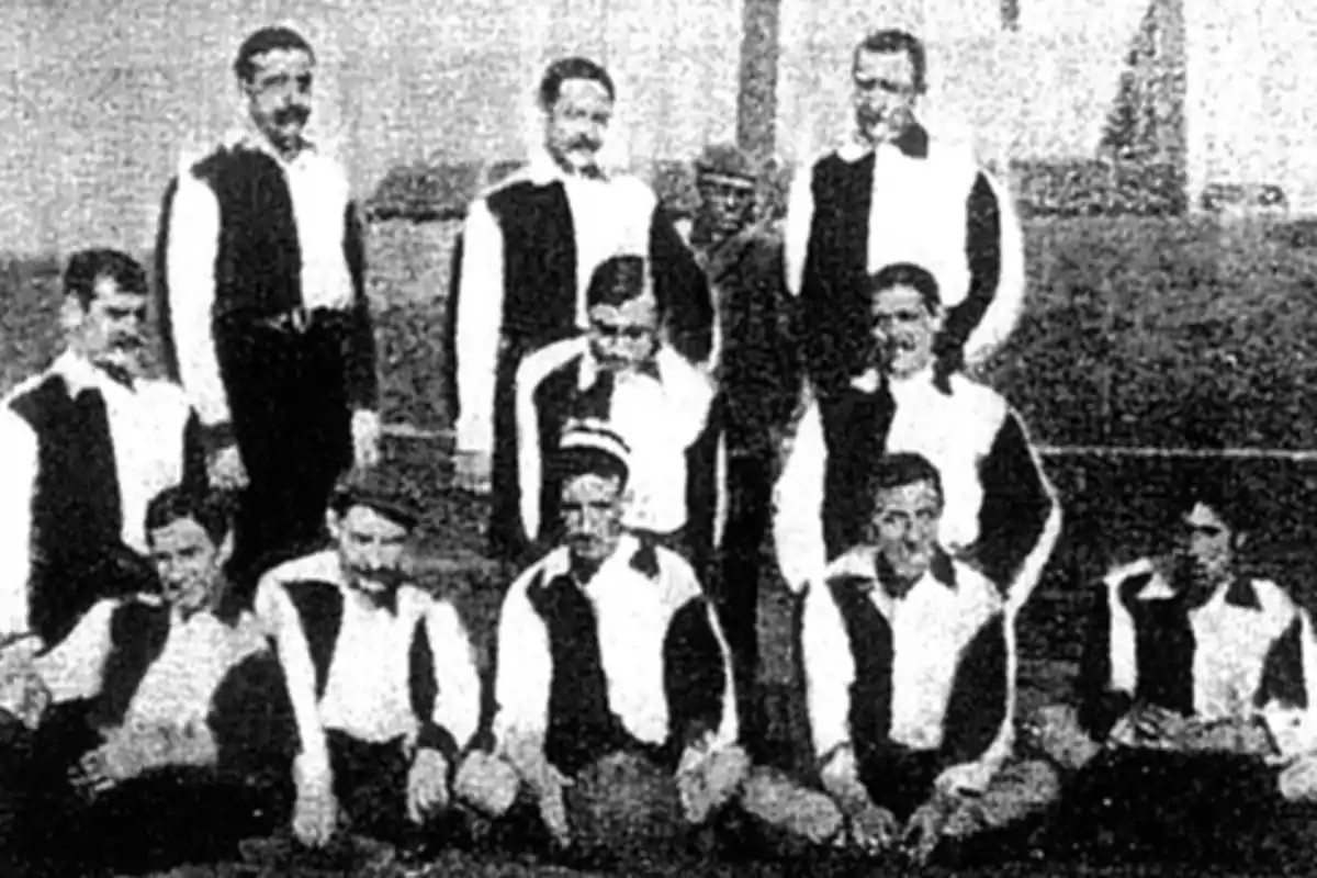 A vintage football team posing for a photo in black and white, with the players wearing long-sleeved uniforms with dark and light colors.