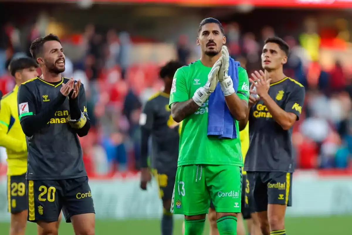 Football players applauding on the field after a match.