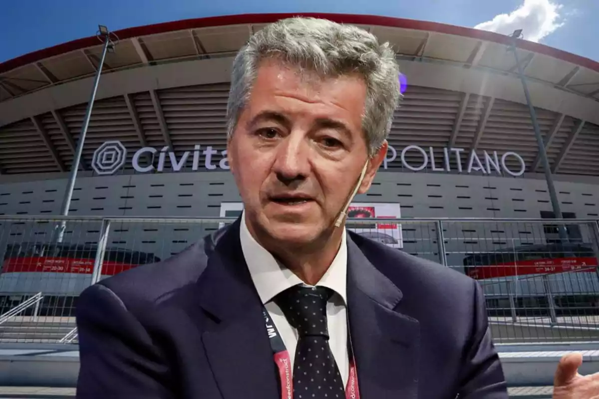 A man in a suit and tie is speaking in front of the Cívitas Metropolitano stadium.