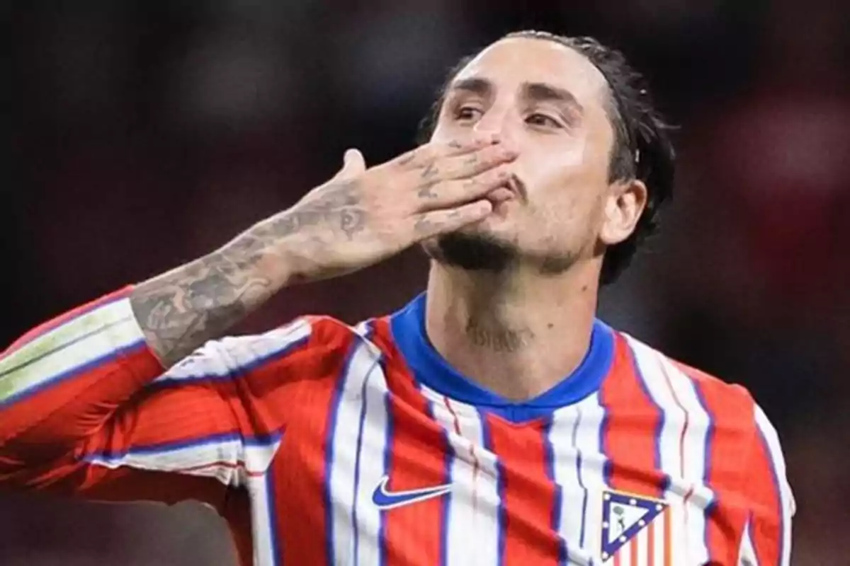 Soccer player in red, white and blue striped uniform, blowing a kiss with his hand.