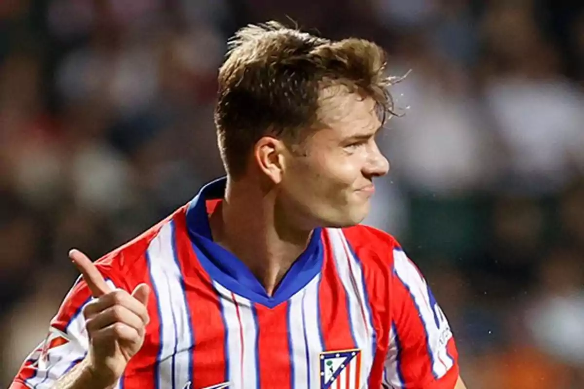 Soccer player with the Atlético de Madrid shirt pointing with his index finger.