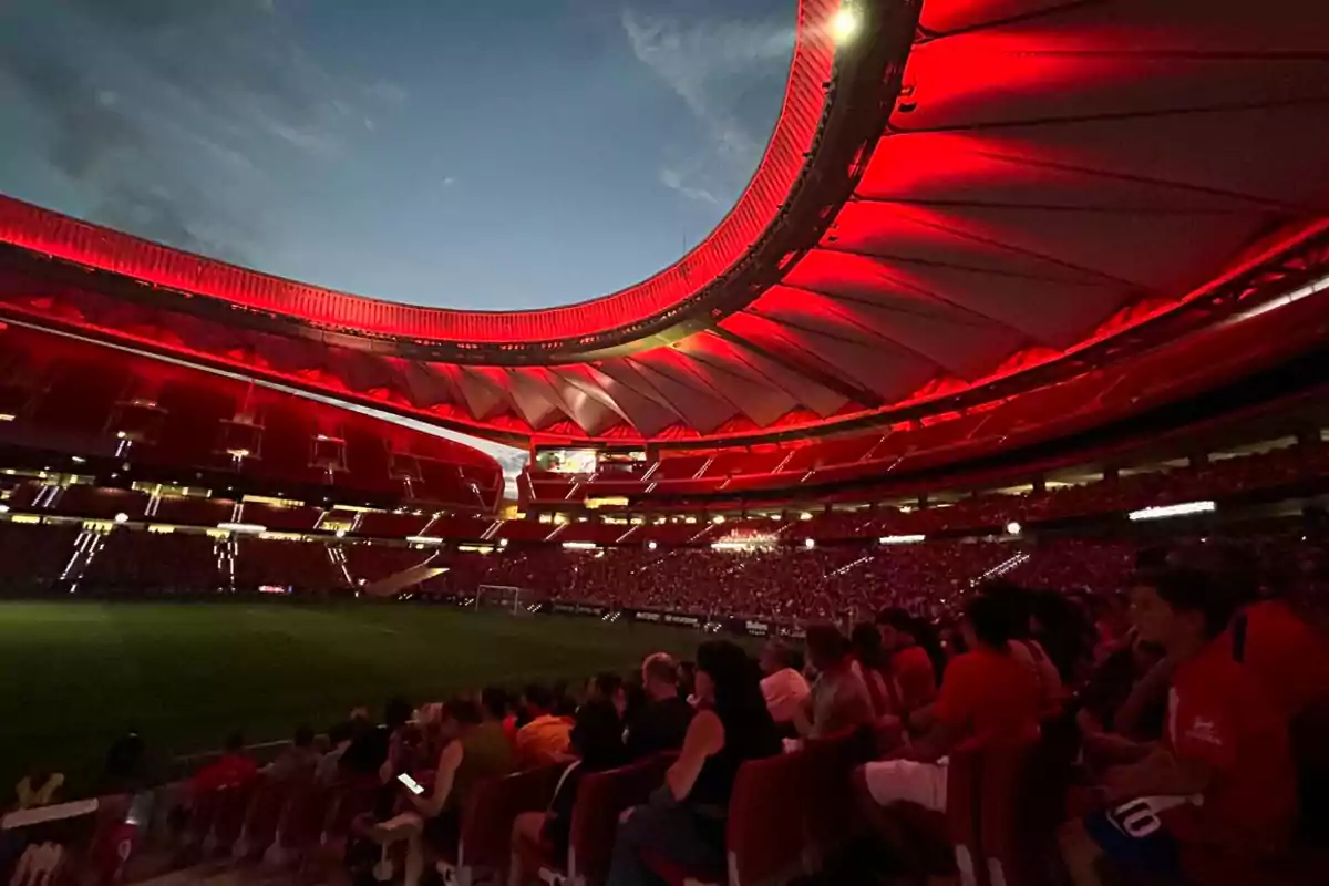 Stadium illuminated with red lights during a night event, with spectators in the stands.