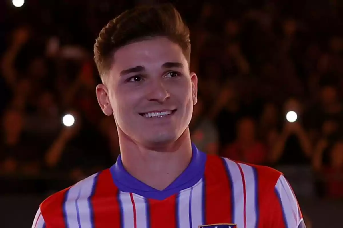 A man in a red, white and blue striped T-shirt smiles as he stands in front of a crowd.