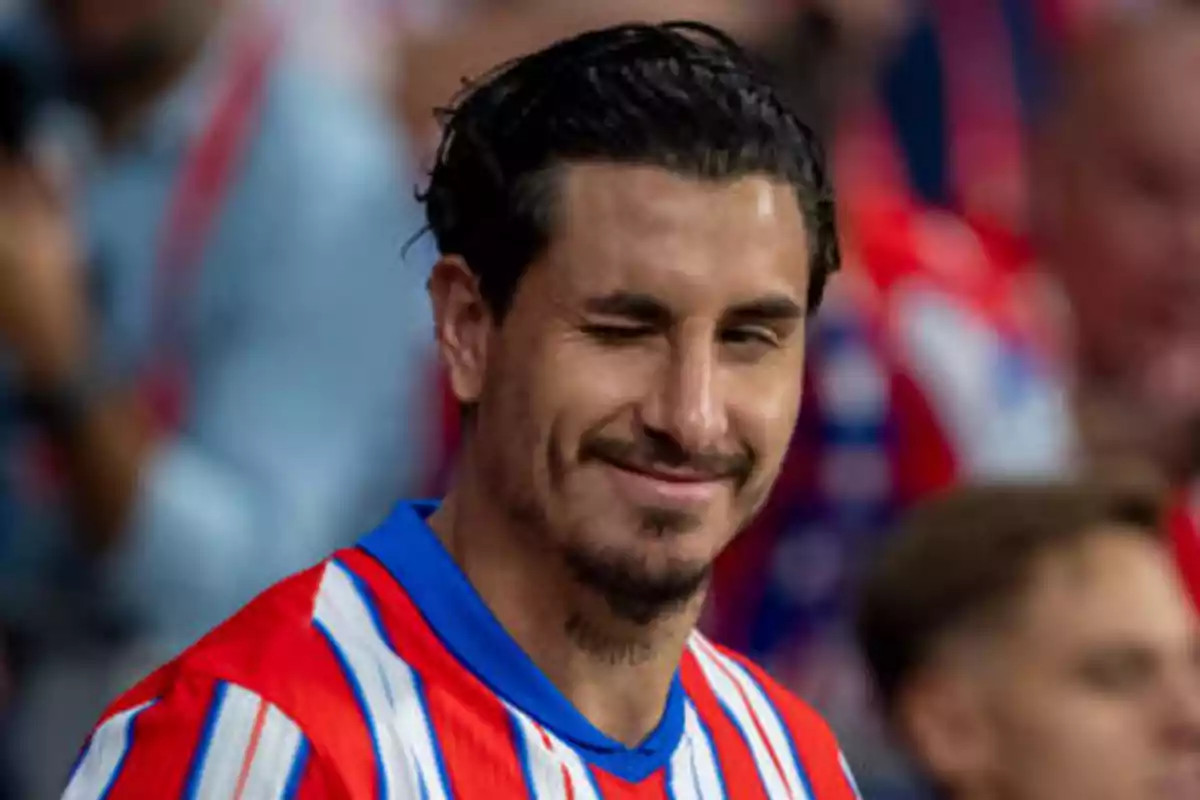 A man in a red, white and blue striped shirt winking.