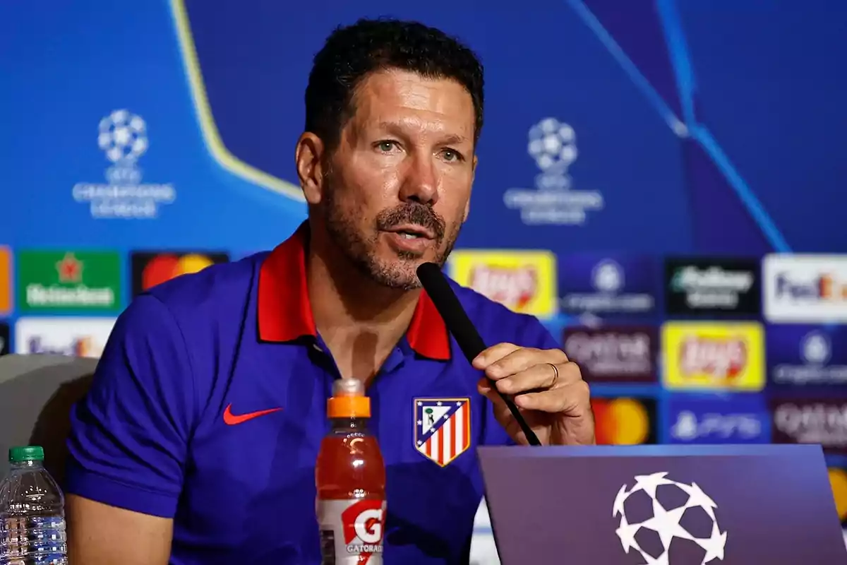 A man wearing an Atletico Madrid shirt speaking at a UEFA Champions League press conference.