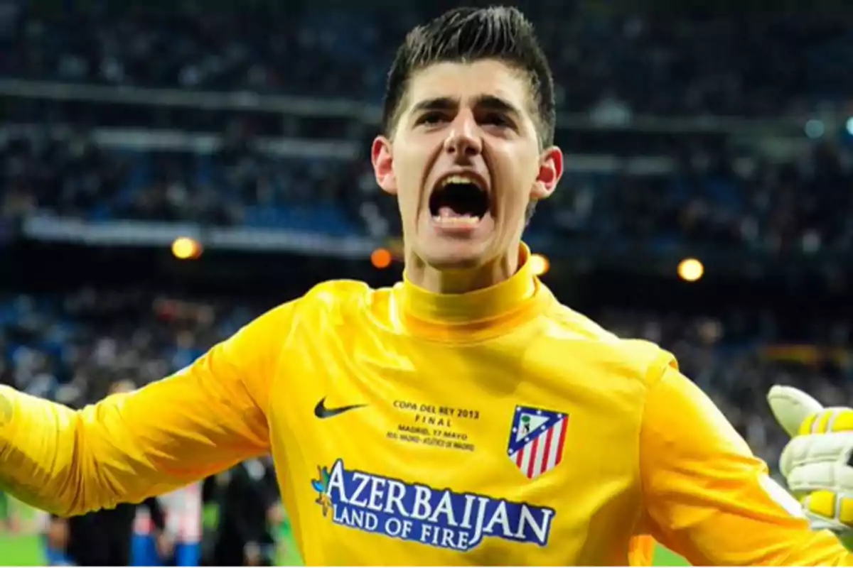 A soccer goalkeeper in a yellow uniform celebrating in a stadium.