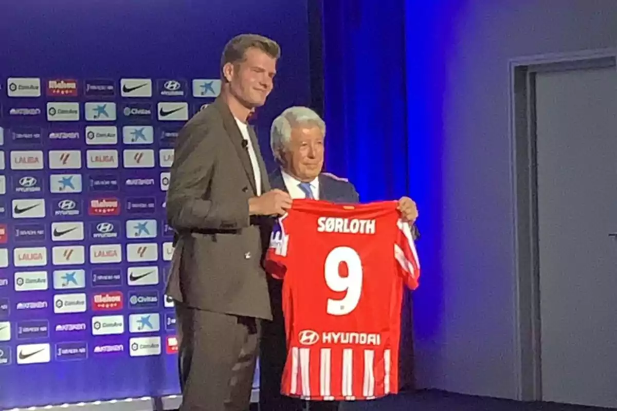 Two people pose in a red football shirt with the name "Sørloth" and the number 9.