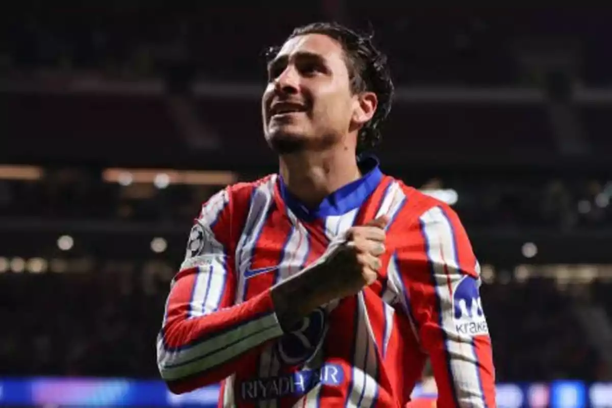 Soccer player in red, white and blue striped uniform celebrating on the field.