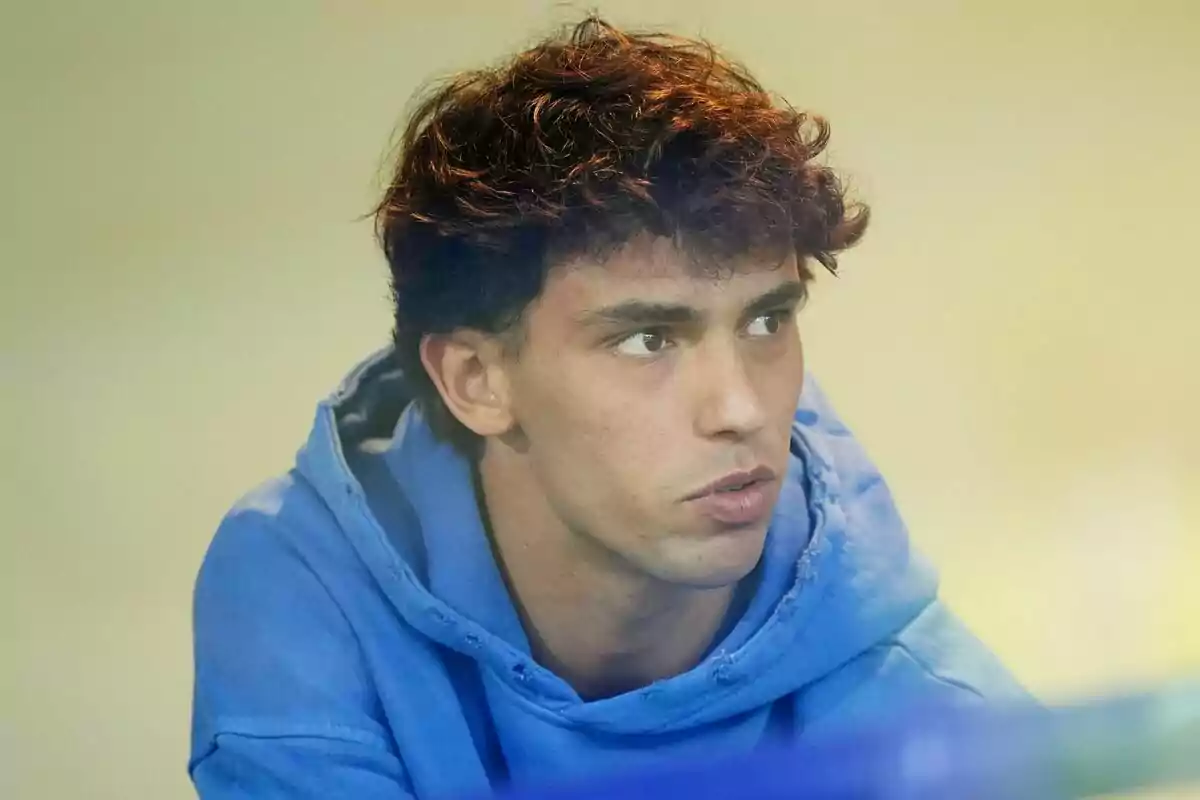 A young man with curly hair and a blue sweatshirt.