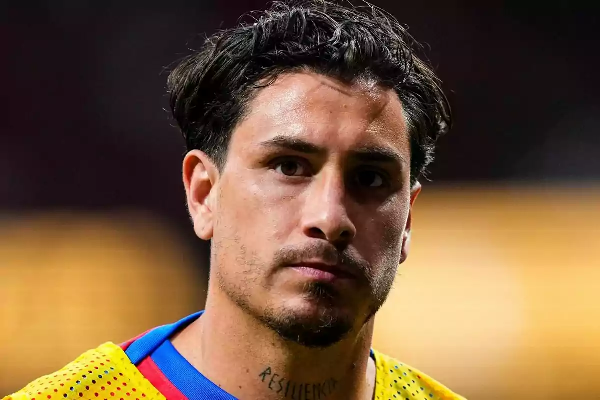 Man in yellow and blue t-shirt with the word "RESILIENCE" tattooed on his neck.