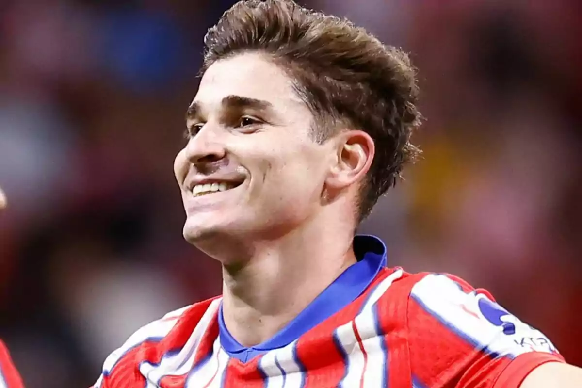 A smiling soccer player in a red, white and blue striped jersey.