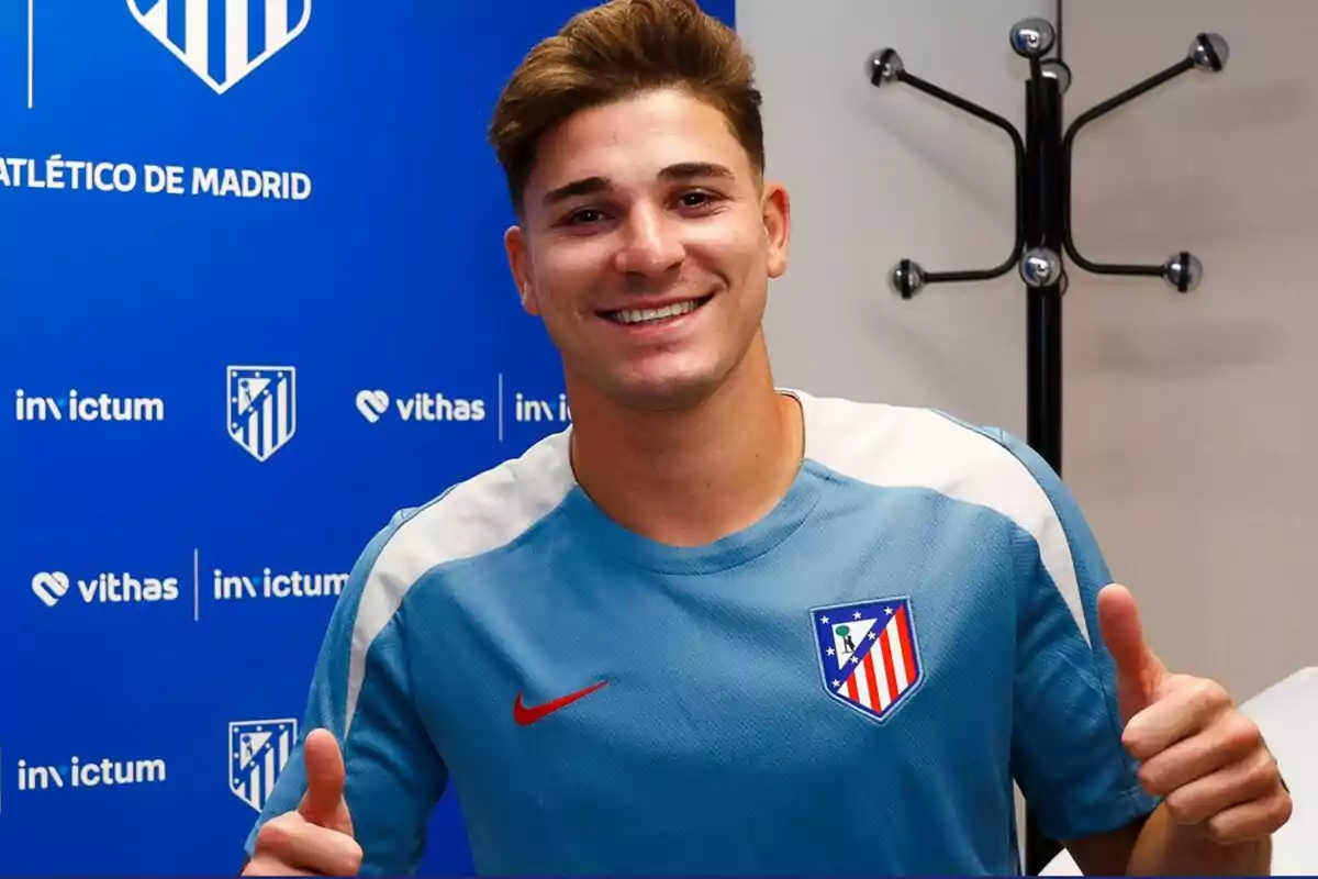 A smiling young man wearing an Atlético de Madrid shirt, posing in front of a blue background with team and sponsor logos.