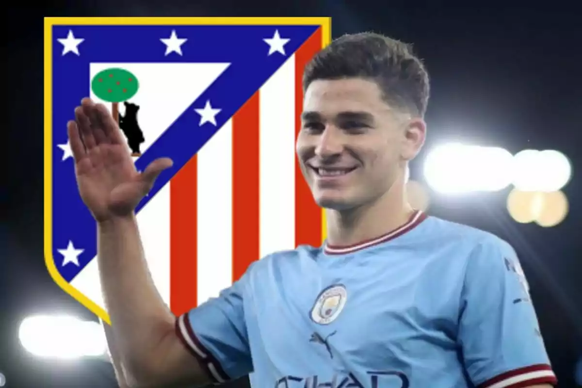 A football player wearing a Manchester City shirt raising his hand, with the Atlético de Madrid shield in the background.