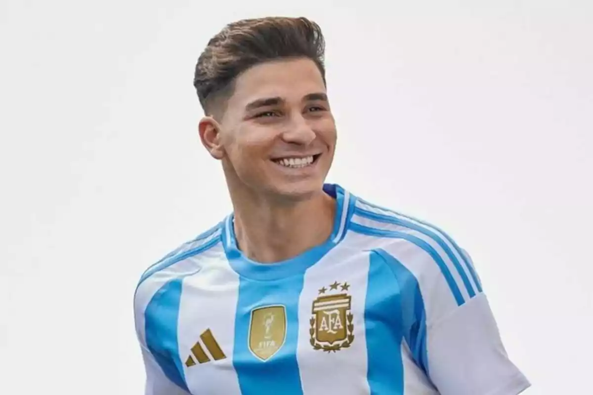 A smiling soccer player wearing the Argentine national team shirt.